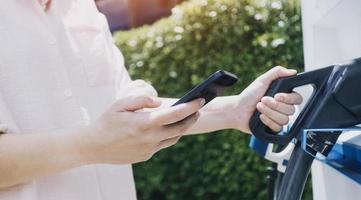 Hand plugging in a charger in an electric car socket.Electric car or ev is charging at station photo