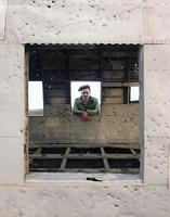 Man with longer hair looking through the window of a plane wreck photo