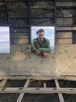 Man with longer hair looking through the window of a plane wreck photo