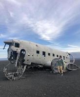 Man in front of an abandoned plane wreck at Solheimasandur, Iceland, in the evening with a dramatic sky in the background photo