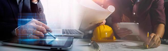 Two colleagues discussing data working and tablet, laptop with on on architectural project at construction site at desk in office photo