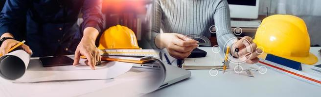 Two colleagues discussing data working and tablet, laptop with on on architectural project at construction site at desk in office photo