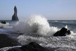 Waves coming in at Reynisfjara Black Beach, Iceland, with rock formations in the background photo