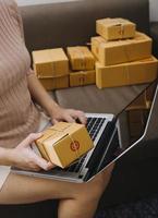 Startup SME small business entrepreneur of freelance Asian woman using a laptop with box Cheerful success Asian woman her hand lifts up online marketing packaging box and delivery SME idea concept photo