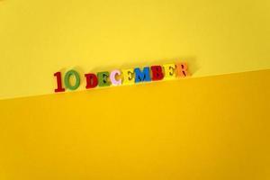 10 de diciembre sobre un fondo amarillo y de papel con letras de madera y multicolores con espacio para texto. foto