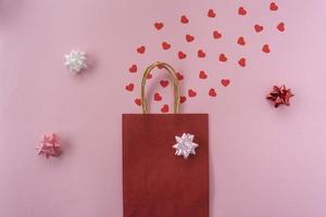 A lot of red hearts as a confetti lying on a pink background for Valentines Day photo