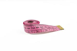 A pink measuring tape lying on a white table photo