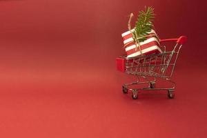 A shopping cart truck with a present inside it standing on a red background photo