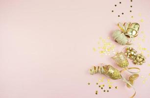 A festive flat lay of golden bows and confetti lying on a pink background photo