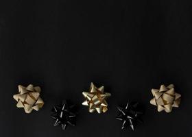 festive flat lay with black and golden bows on a black background photo