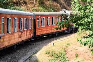 tren de juguete moviéndose en las laderas de las montañas, hermosa vista, una montaña lateral, un valle lateral moviéndose en ferrocarril hacia la colina, entre bosques naturales verdes. tren de juguete de kalka a shimla en india, tren indio foto