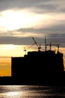 Industrial scene concept of city in riverside view. Cranes are working during construction process in sunset. photo