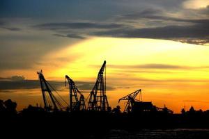 Industrial scene concept of city view. Cranes are working during construction process in sunset. photo