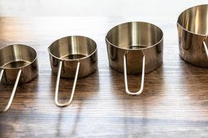 Set of measuring cups made from stainless with a handle on wooden tabletop photo