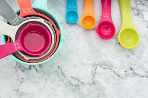 un juego de tazas medidoras y cucharas medidoras que se usan para cocinar se colocan sobre una mesa de mármol en la vista superior, estilo plano. foto