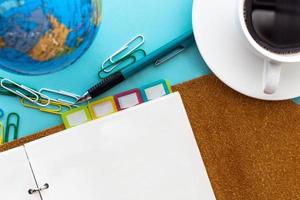 Blank page planner with mechanical pencil and black coffee on blue background in top view photo