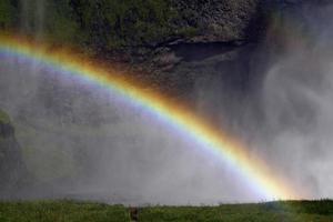 A rainbow in front of Seljalandsfoss waterfall on the southern coast of Iceland on a sunny day photo