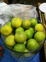 Lime with lots of green and yellow rinds in a glass jar. photo