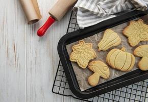 Cookies shaped like pumpkin and leaves on rustic wood background photo