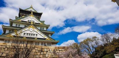 foto paisajística del castillo de osaka en primavera, donde todavía hay algunos cerezos en flor.