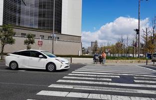 Osaka, Japan on April 10, 2019. Situation at a pedestrian crossing, where a white sporty car stops when a couple riding a bicycle crosses at the crossing. photo