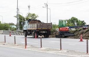 Backhoe is digging soil on road photo