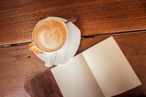 A cup of hot coffee with latte art on the surface placed in the wooden table. photo