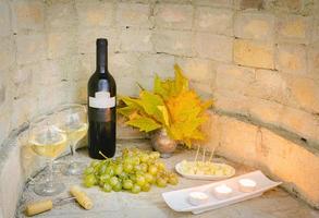 botella de vino con velas y queso en otoño foto