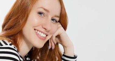 Red haired girl with close up macro face and perfect white teeth smile isolated on white background. Woman beauty and skin care. No make up concept. Redhead beautiful female. Selective focus. Banner photo