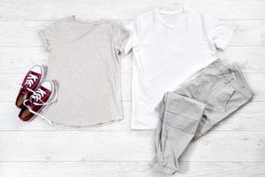 camiseta blanca y zapatillas de deporte masculinas y femeninas. maqueta de camiseta plana con accesorios de verano. ropa para mujeres y hombres sobre fondo de piso de madera. copie el espacio plantilla lienzo en blanco. foto