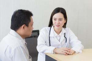 Asian woman doctor with a white lab coat give counsel with a man patient. photo