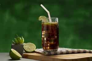 Cuba Libre drink with lime and ice on rustic wooden table photo