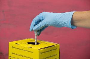 contaminated hospital waste collection box with hand placing a syringe photo