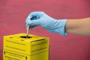 contaminated hospital waste collection box with hand placing a syringe photo