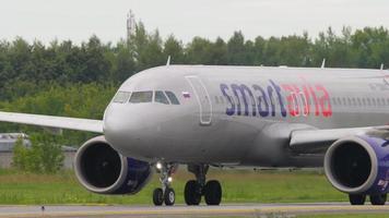 NOVOSIBIRSK, RUSSIAN FEDERATION JULY 15, 2022 - Middle shot, airbus A320neo of Smartavia rides on the taxiway at Tolmachevo Airport, Novosibirsk. Airplane taxiing on runway video