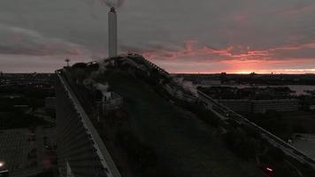 vue aérienne de l'amager bakke, centrale de valorisation énergétique des déchets de copenhill avec pistes de ski vertes avec toboggans et kickers au coucher du soleil. usine d'énergie écologique verte. video