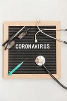 Text phrase Coronavirus syringe and stethoscope on black letter board background. Novel coronavirus 2019-nCoV, MERS-Cov middle East respiratory syndrome coronavirus originating in Wuhan China photo