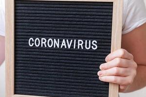 mano de mujer sosteniendo un tablero de letras negro con frase de texto coronavirus. nuevo coronavirus 2019-ncov, mers-cov síndrome respiratorio de oriente medio coronavirus originario de wuhan china foto