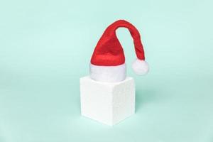 Simply minimal composition winter object Santa hat and cube shapes geometric form podium isolated blue pastel background. Christmas New Year december time for celebration concept. Mockup, copy space photo