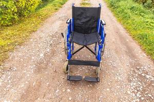 Empty wheelchair standing on road waiting for patient services. Wheel chair for people person with disability parked outdoor. Accessible for person with disability. Health care medical concept. photo