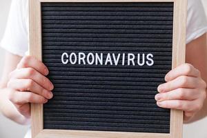 mano de mujer sosteniendo un tablero de letras negro con frase de texto coronavirus. nuevo coronavirus 2019-ncov, mers-cov síndrome respiratorio de oriente medio coronavirus originario de wuhan china foto