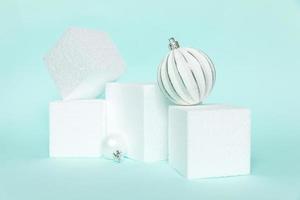 Simply minimal composition winter objects ornament and cube shapes geometric form podium isolated blue pastel background. Christmas New Year december time for celebration concept. Mockup, copy space photo