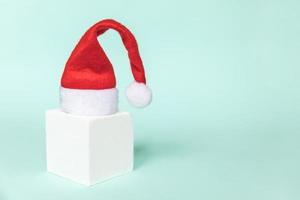Simply minimal composition winter object Santa hat and cube shapes geometric form podium isolated blue pastel background. Christmas New Year december time for celebration concept. Mockup, copy space photo