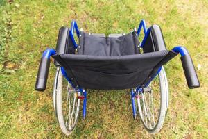 Empty wheelchair standing in hospital park waiting for patient services. Wheel chair for person with disability parked outdoor. Accessible for person with disability. Health care medical concept. photo