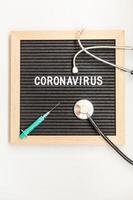Jeringa y estetoscopio de coronavirus de frase de texto sobre fondo de tablero de letras negras. nuevo coronavirus 2019-ncov, mers-cov síndrome respiratorio de oriente medio coronavirus originario de wuhan china