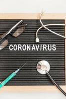 Jeringa y estetoscopio de coronavirus de frase de texto sobre fondo de tablero de letras negras. nuevo coronavirus 2019-ncov, mers-cov síndrome respiratorio de oriente medio coronavirus originario de wuhan china