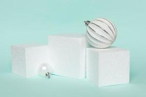 Simply minimal composition winter objects ornament and cube shapes geometric form podium isolated blue pastel background. Christmas New Year december time for celebration concept. Mockup, copy space photo