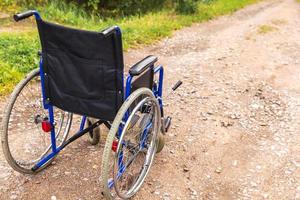 silla de ruedas vacía parada en la carretera esperando servicios para pacientes. silla de ruedas para personas con discapacidad estacionada al aire libre. accesible para persona con discapacidad. concepto médico de atención médica. foto