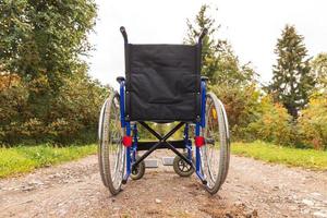 silla de ruedas vacía parada en la carretera esperando servicios para pacientes. silla de ruedas para personas con discapacidad estacionada al aire libre. accesible para persona con discapacidad. concepto médico de atención médica. foto