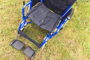 Empty wheelchair standing in hospital park waiting for patient services. Wheel chair for person with disability parked outdoor. Accessible for person with disability. Health care medical concept. photo
